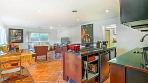 A modern kitchen with a central island, a dining area with a table and chairs, and a living room with a sofa and a coffee table.