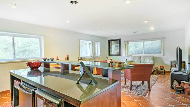 A modern kitchen with a central island, built-in appliances, and large windows providing natural light.