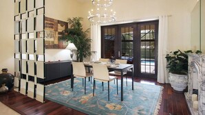A dining area with a table set for four, a chandelier, a large potted plant, and a view through a glass door. - Country Club Residence by 123cape VR (Fort Myers)