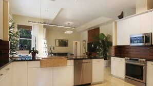 A modern kitchen with white cabinetry, stainless steel appliances, and a central island. - Country Club Residence by 123cape VR (Fort Myers)