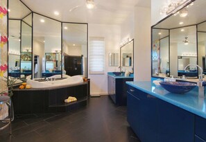 Een moderne badkamer met een groot bad, een aparte douche en een wastafel met een grote spiegel.