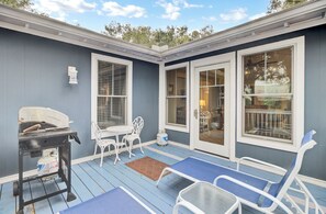 Une terrasse couverte avec un barbecue, des sièges d’extérieur et une vue sur le jardin.