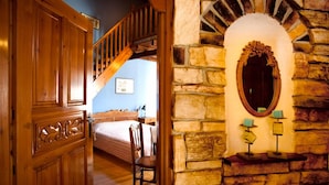 A wooden door leading to a bedroom with a bed, a chair, and a staircase. - Archontiko Panagoula (Volos)