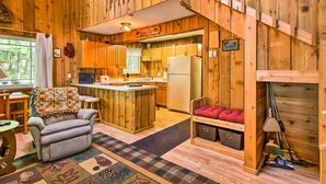 Eine gemütliche Küchenzeile im Blockhausstil mit Holzwänden, einer zentralen Kochinsel und einem Essbereich mit Tisch und Stühlen.