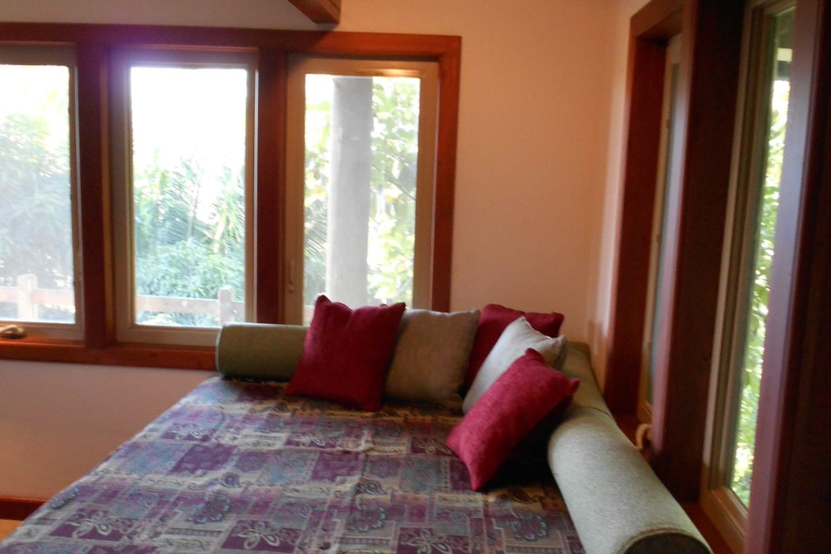 A room with a bed, large windows, and an air conditioning unit.