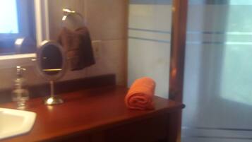 A bathroom with a wooden vanity, a mirror, a towel, and a shower area.
