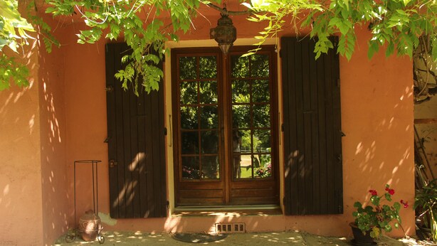 A building entrance with a wooden door, a metal lantern, and a potted plant. - Residence with character (Pont-Saint-Esprit)