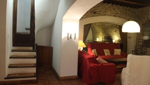 A cozy room with a stone wall, a red sofa, a white armchair, and a staircase. - Residence with character (Pont-Saint-Esprit)