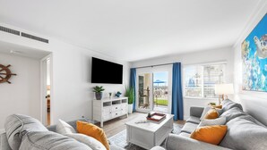 A modern living room with a grey sofa set, a white coffee table, and a flat-screen TV mounted on the wall. - 112-Keep Calm & Carry on Vacationing! Ground floor Private walk out patio (Destin)