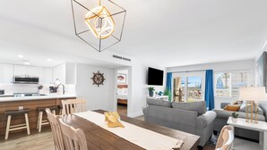 A modern kitchen with white cabinets, a wooden dining table, and a unique geometric light fixture. - 112-Keep Calm & Carry on Vacationing! Ground floor Private walk out patio (Destin)