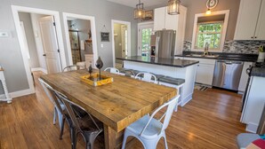 A modern kitchen with a central island, stainless steel appliances, and a wooden dining table with chairs. - Near Indiana Dunes w/ pool, tennis court, golf cart (Michigan City)