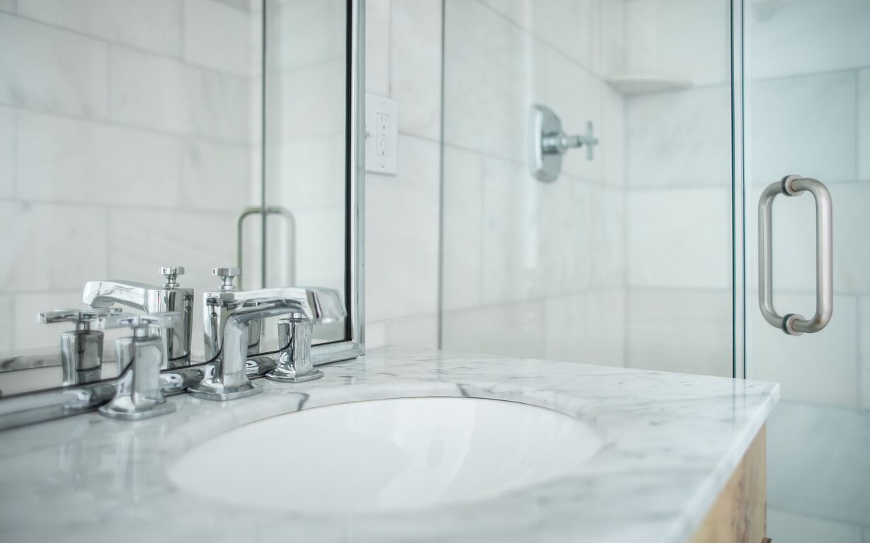 Un bany modern amb un rentapans blanc, aixetes cromades i una cabina de dutxa de vidre.