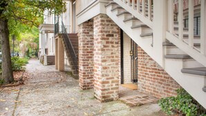 Ein Gebäude mit Ziegelaußenwand, einer Treppe, die zum Eingang führt, und einem Weg mit herabgefallenen Blättern.