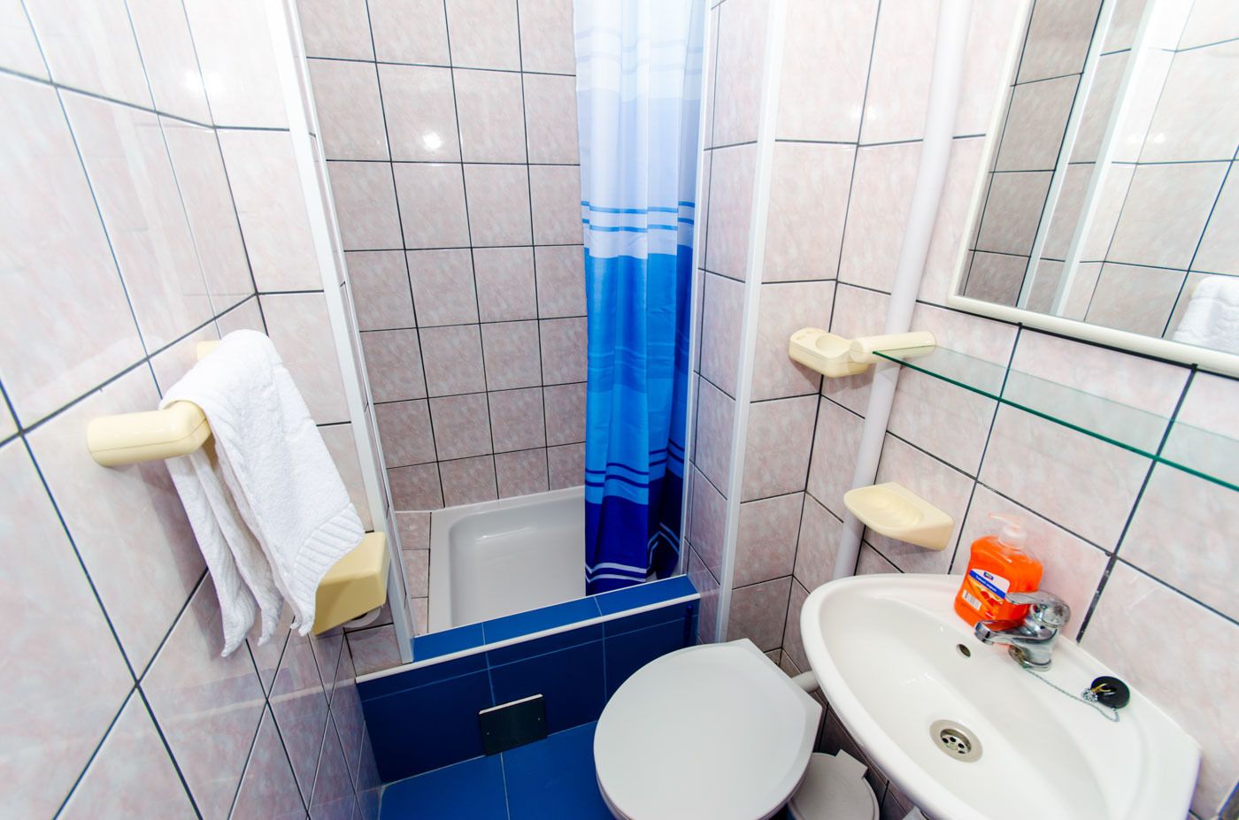 A small bathroom with a shower, toilet, and sink.