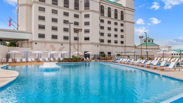 Un hôtel doté d’un grand espace piscine, de nombreuses chaises longues et de parasols.