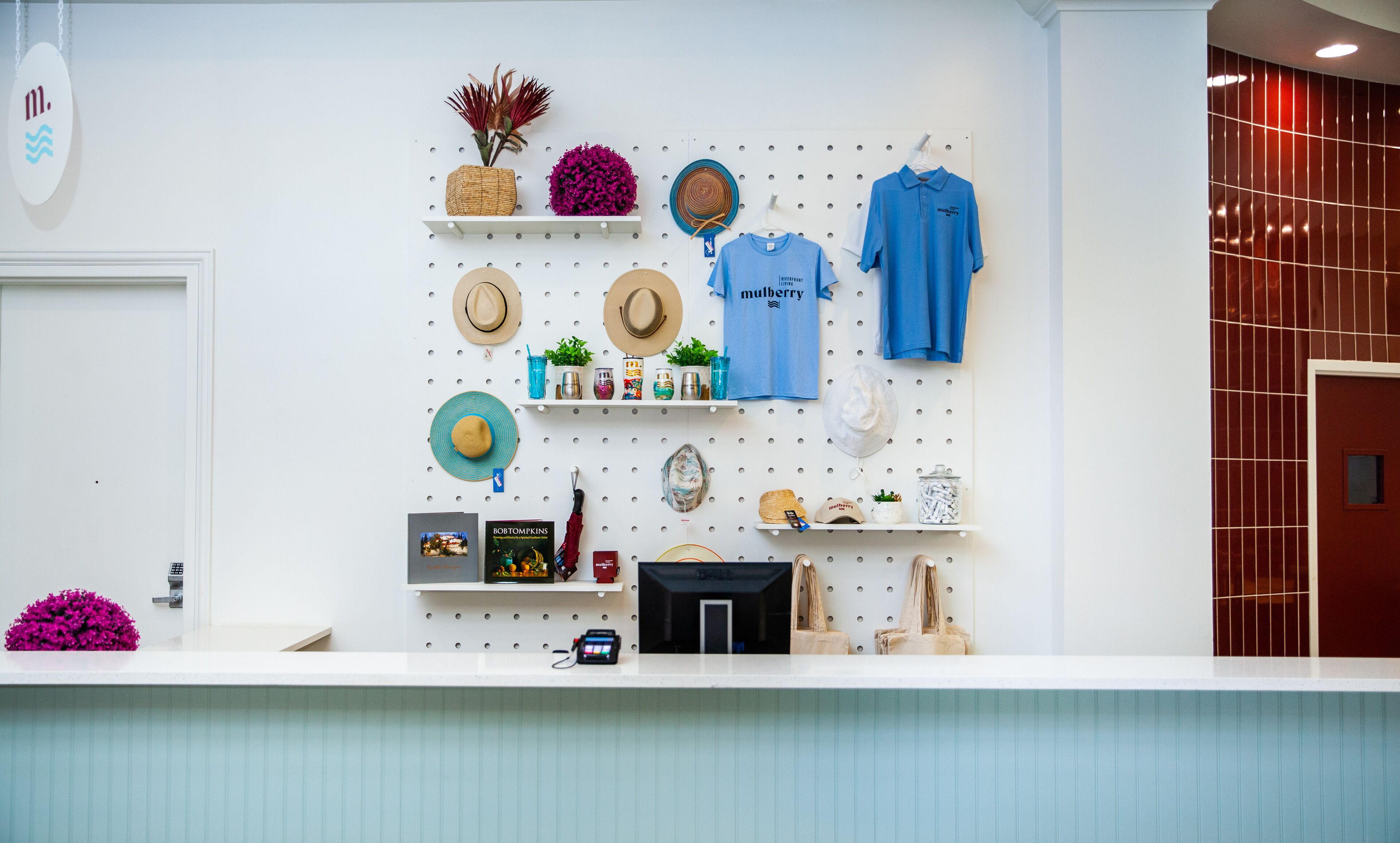 A hotel reception area with a pegboard wall displaying various items such as hats, a blue shirt, and decorative objects.