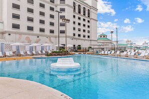 A swimming pool with lounge chairs and umbrellas, surrounded by a building with multiple windows and a dome structure. - Mulberry, a Wyndham Hotel (Vicksburg)