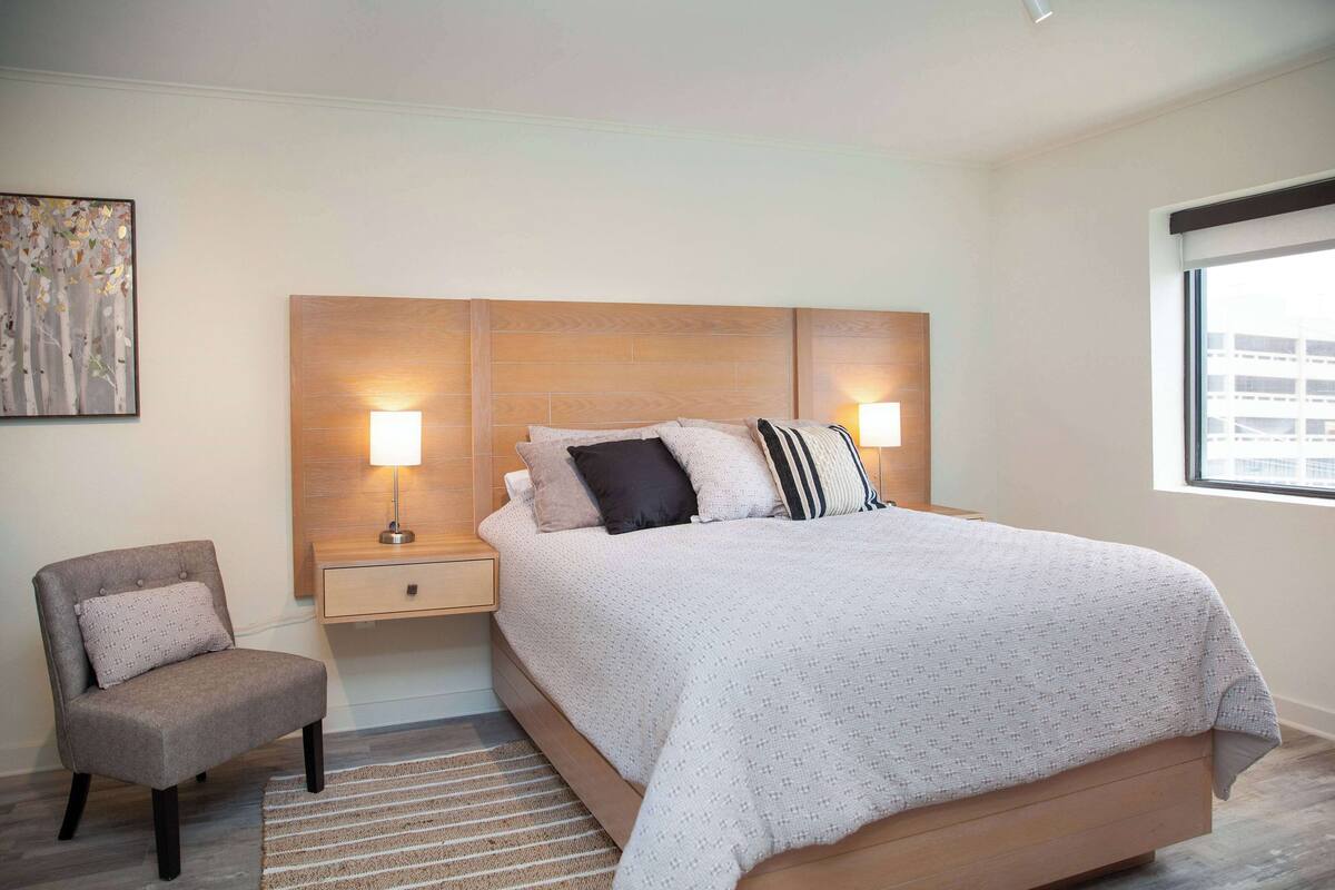 A bedroom with a bed, nightstands, a chair, and a window.