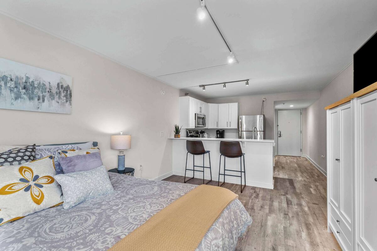 A modern apartment with a bedroom, kitchenette, and a dining area.