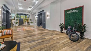Un hall d’entrée spacieux avec un plancher en bois, un vélo et une enseigne fixée au mur sur laquelle on peut lire « mulberry ».