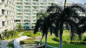 A modern hotel with a central courtyard, a swimming pool, and a well-maintained garden.