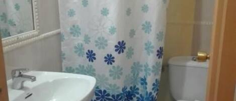 A bathroom with a white sink, a toilet, and a shower curtain with a floral pattern.