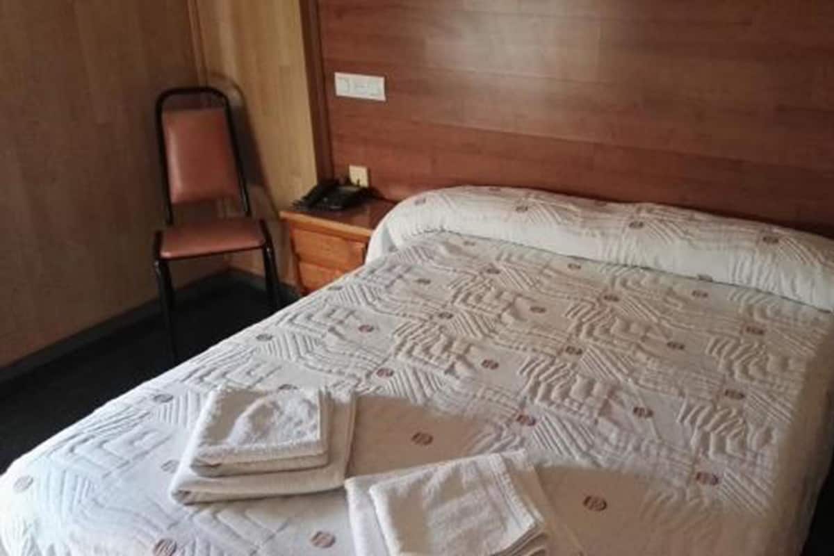 Ein Hotelzimmer mit einem Bett, einem Sessel und einem Nachttisch mit Telefon.
