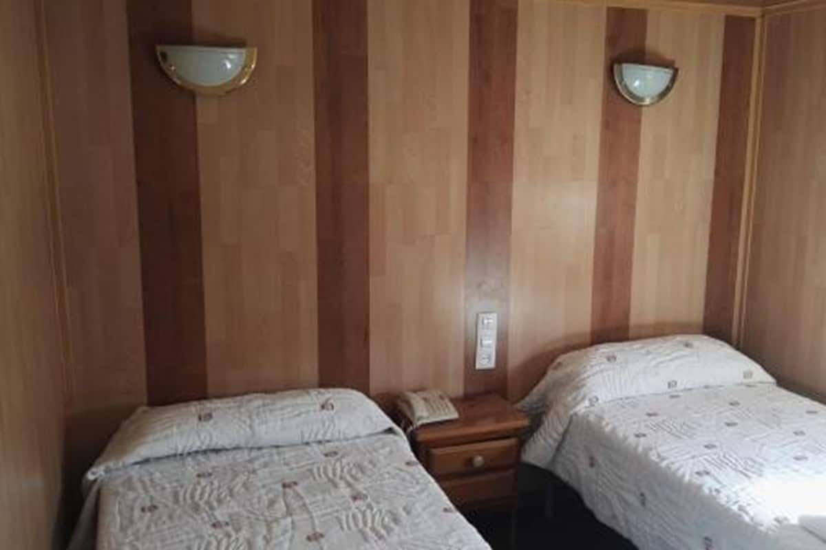 Ein Zimmer mit zwei Betten, Holzwandverkleidung und zwei Wandleuchten.