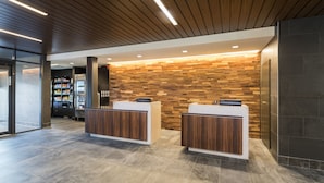 A reception area with two wooden reception desks, a wall with a wooden panel design, and a modern lighting fixture.