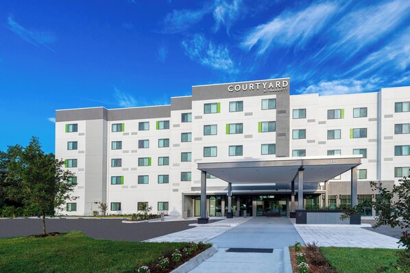 Ein Courtyard by Marriott Hotel mit moderner Fassade, mehreren Etagen und einem überdachten Eingang.