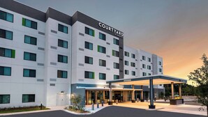 A Courtyard by Marriott hotel with a modern design, featuring a covered entrance and a landscaped area in front.