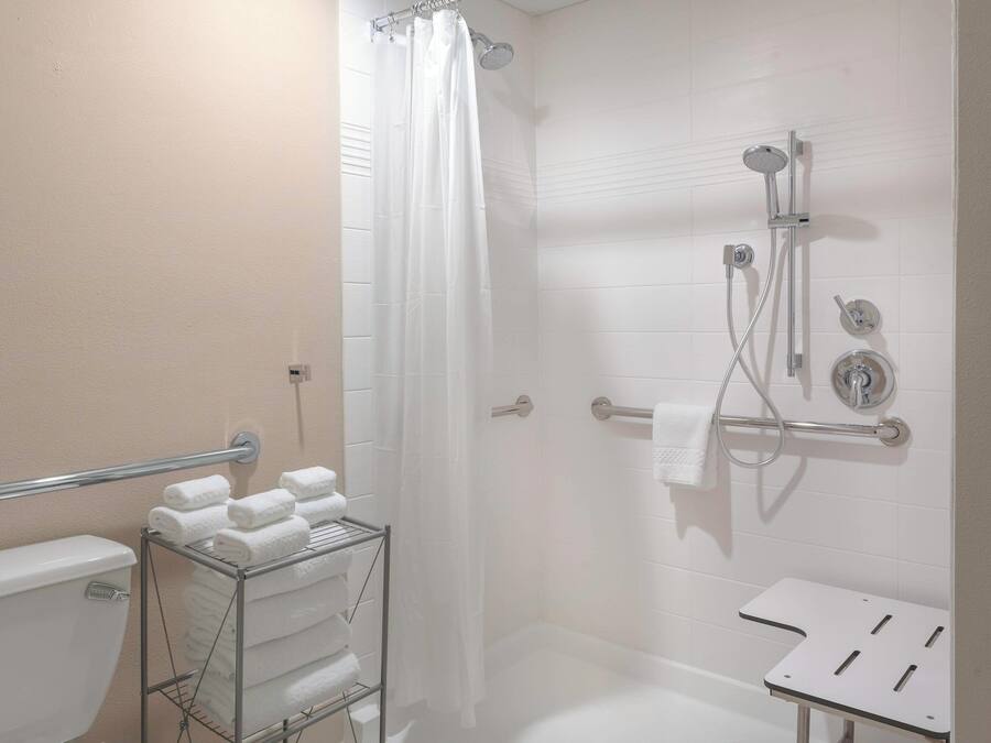 Une salle de bain moderne équipée d’une douche, de toilettes et d’un porte-serviettes où sont soigneusement pliées les serviettes.