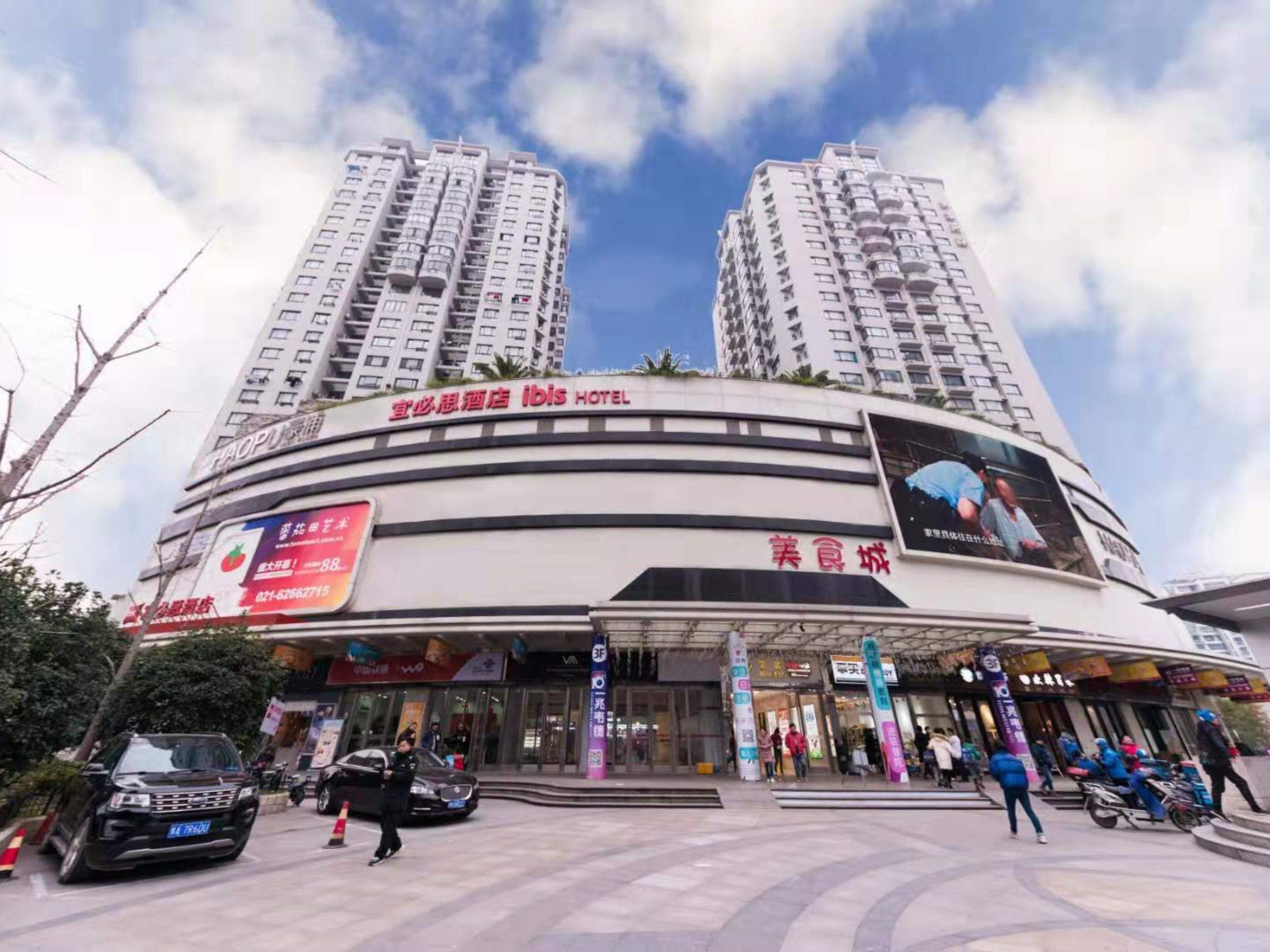A hotel with a modern facade, multiple floors, and a prominent sign for the ibis hotel.