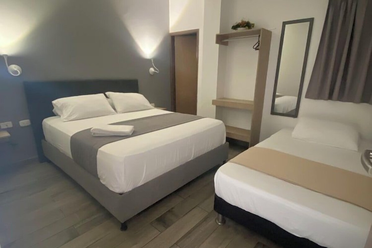 Une chambre d’hôtel avec deux lits, une table de chevet, un miroir et un appareil de climatisation.