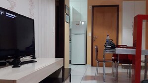 Uma cozinha moderna com televisão, mesa de jantar, cadeiras e frigorífico.