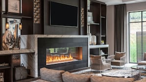 A modern living room with a fireplace, comfortable seating, and a large TV mounted on the wall.