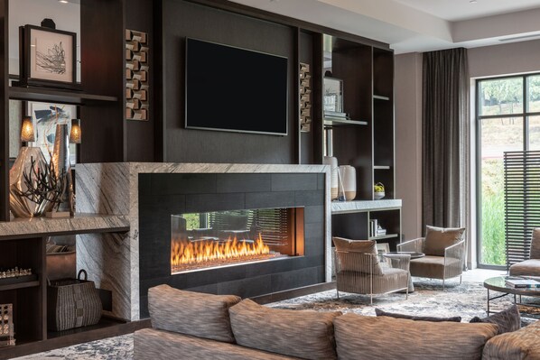 A modern living room with a fireplace, comfortable seating, and a large TV mounted on the wall.