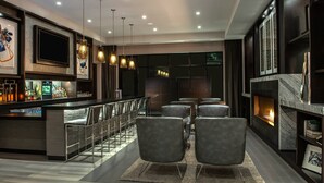 A modern bar area with a long counter, bar stools, and a fireplace.