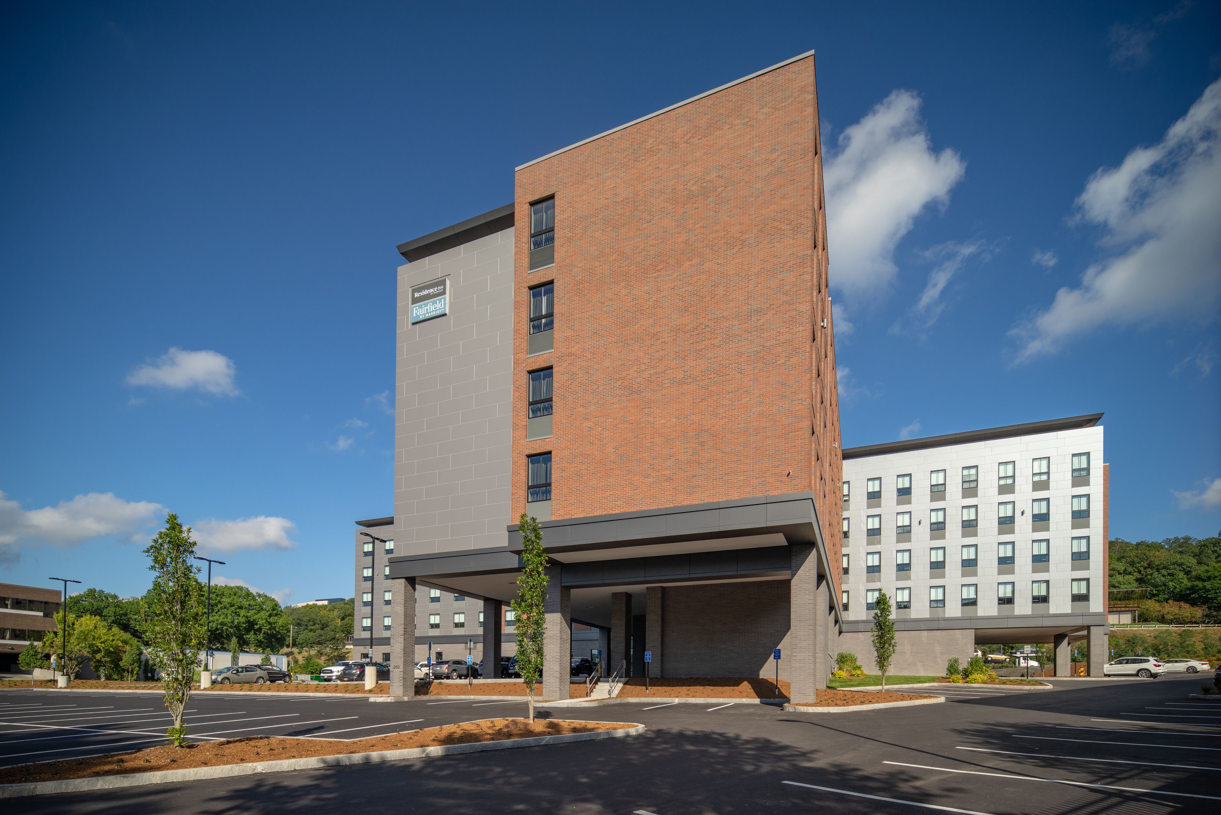 A modern hotel with a brick facade, a covered entrance, and a parking lot.