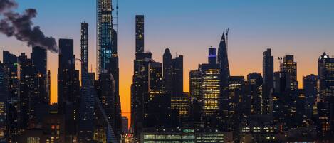A city skyline at dusk with high-rise buildings and a body of water in the foreground.