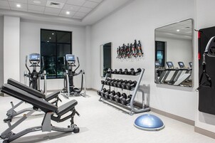 Un gimnasio con equipo de ejercicio, una cinta de correr y un espejo grande.