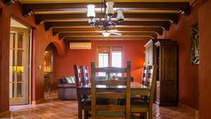 Un espace repas avec une table et des chaises en bois, un lustre et un ventilateur de plafond.