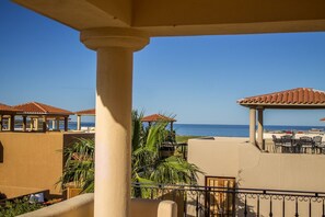 Un balcon avec vue sur la mer, des palmiers et des sièges d’extérieur.