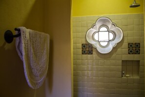 Un baño con toallero, lámpara decorativa y baldosas estampadas.