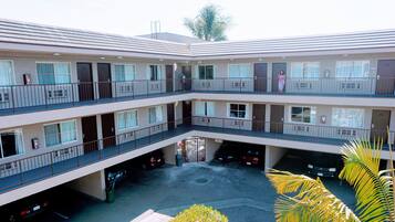 Un motel de varios pisos con un patio central, balcones y espacios para estacionar.
