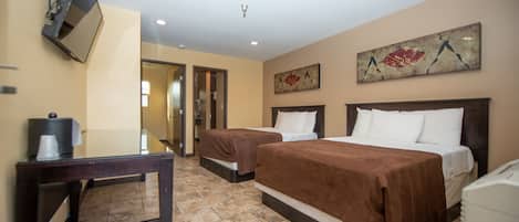 A hotel room with two beds, a desk, and a TV.