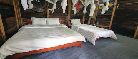 Una habitación con dos camas, un mosquitero y una pared de madera.