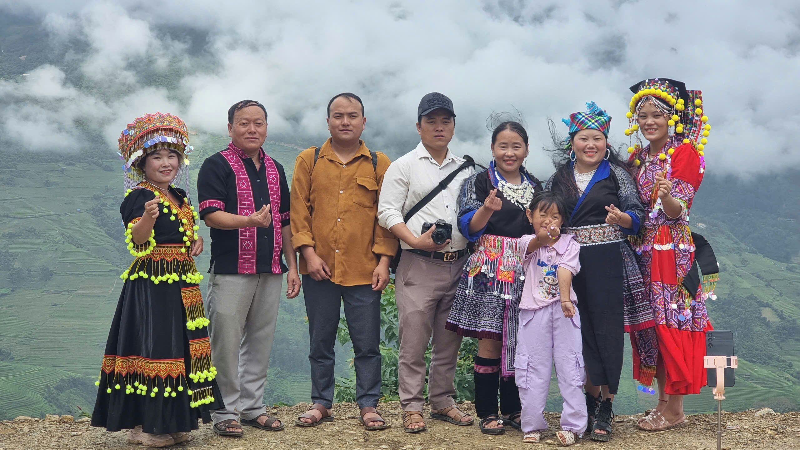 A group of people in traditional attire standing on a mountain with a misty background.