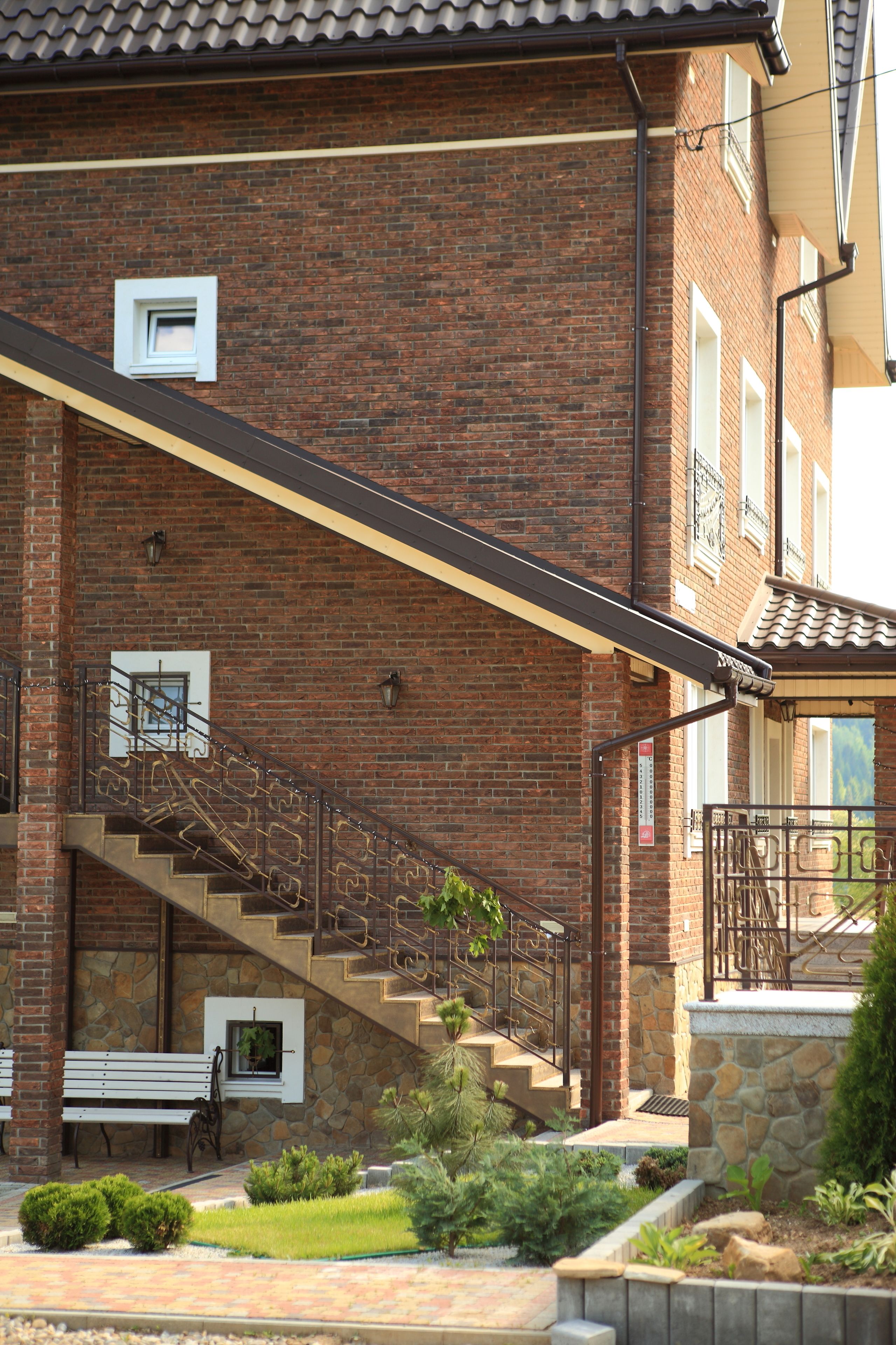 A brick building with a stone staircase, a bench, and a small garden area.