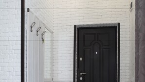 A hallway with a white brick wall, a black door, and a bench with a light-colored bench seat. - FAVAR Carpathians (Skhidnytsia)
